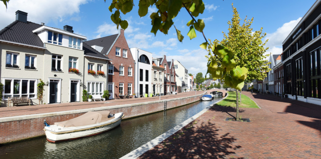 Sloot met kade waar bootjes liggen en grenzend aan de kade staan woningen 