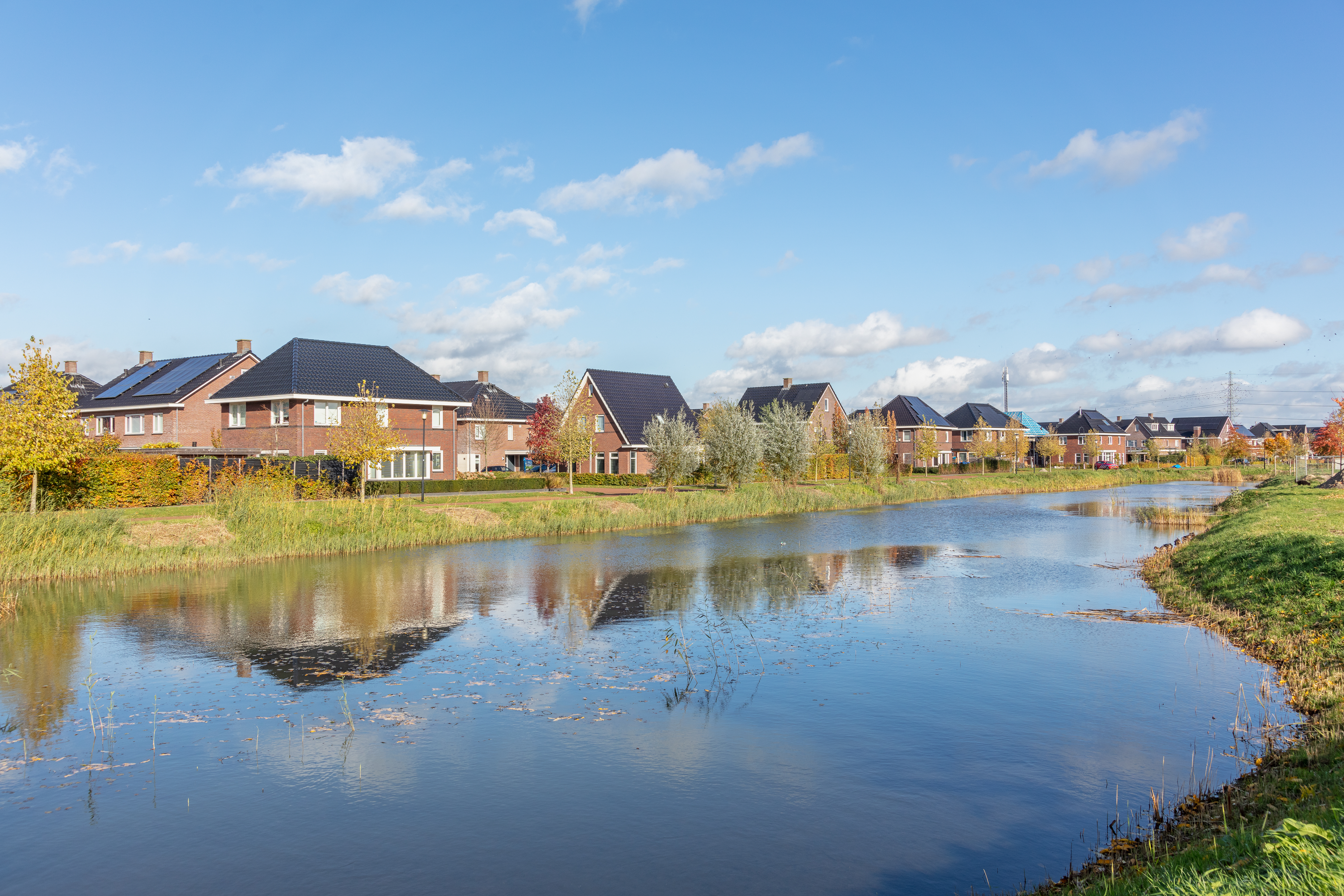 Foto genomen vanaf de waterkant waarbij je het nieuwbouw project Nagtegael kan zien en de groene omgeving
